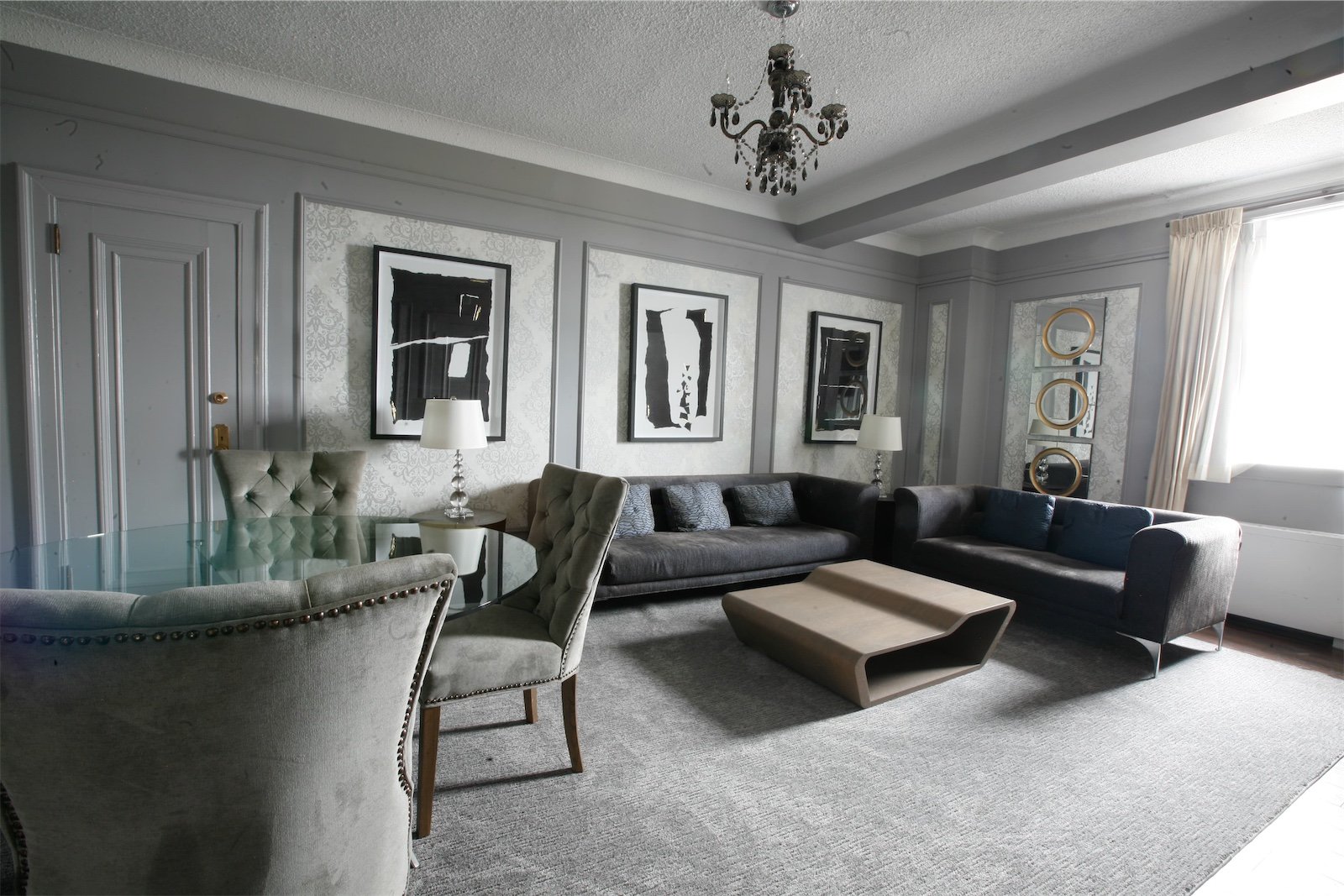 Hotel suite living room with a sectional sofa, framed artwork and a chandelier