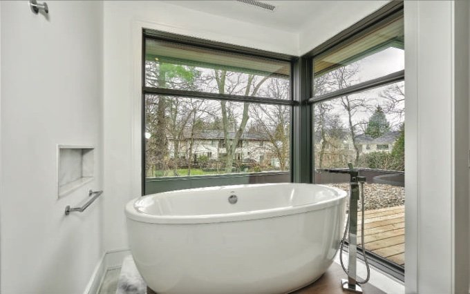 Freestanding bath beside a corner window in the ensuite bathroom