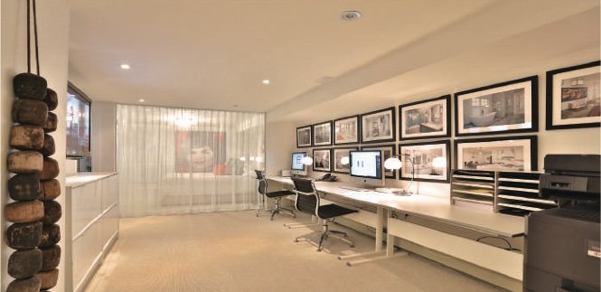 Home office with a wall of framed prints and a long desk