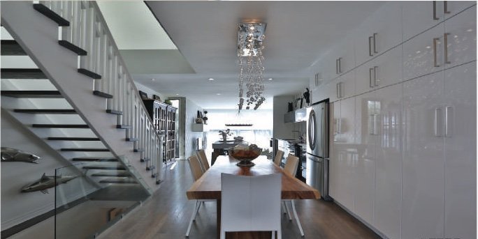 Open stair beside a dining table and a long run of white cabinetry